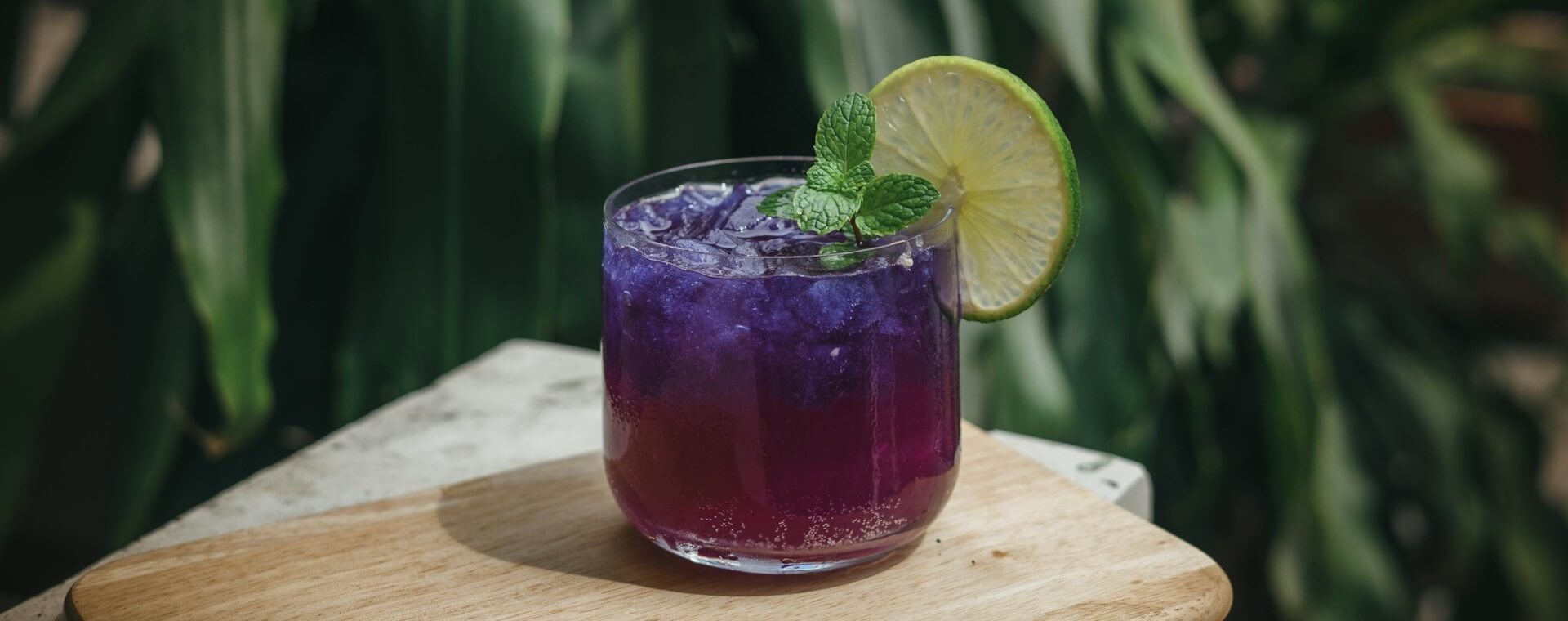 стакан с фиолетовым напитком долькой лайма и мятой